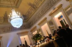 a group of people standing in a room with chandelier