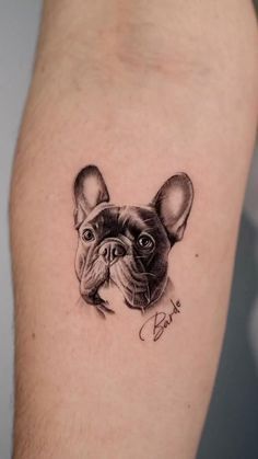 a small black and white dog tattoo on the arm