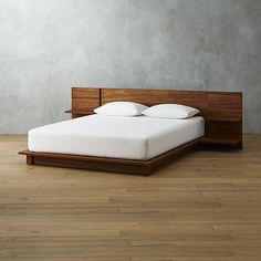 a bed with white pillows and wooden headboard