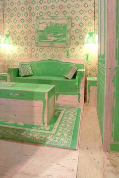 a living room with green furniture and wallpaper