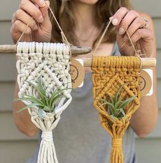 a woman is holding up two macrame plant holders