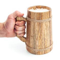 a hand holding a wooden mug with white foam