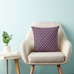 an orange pillow sitting on top of a white chair next to a potted plant