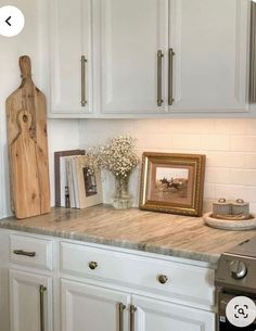 a kitchen with white cabinets and wooden cutting board