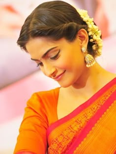 a woman in an orange sari looking at her cell phone