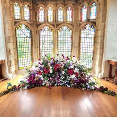 an arrangement of flowers is arranged on the floor in front of two large stained glass windows