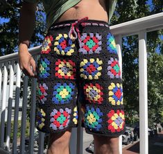 a man standing on a porch wearing shorts with crochet flowers all over them