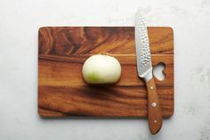 an onion on a cutting board next to a knife