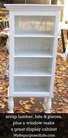 a white bookcase sitting on top of a pile of leaves