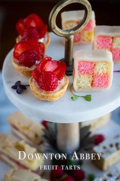 small desserts on a white cake stand with fruit tarts in the middle and an antique key to hold them