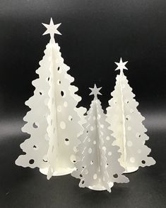 three white paper christmas trees with stars on them, one in the shape of a tree