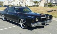 an old black car parked in a parking lot