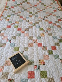 a quilted bed with a chalkboard on the top of it and a pillow