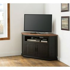 a flat screen tv sitting on top of a wooden entertainment center next to a window