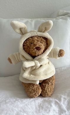 a teddy bear in a bunny costume sitting on a bed