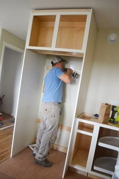 a man in blue shirt and grey pants working on a wall unit with wood paneling