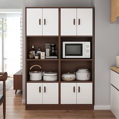 a microwave oven sitting on top of a wooden shelf next to white cupboards in a kitchen