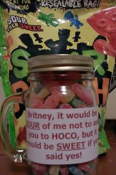 a jar filled with lots of candy sitting on top of a table next to a bag of gummy bears