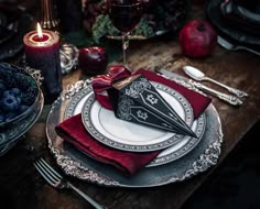 a table set with silverware, red napkins and black paper napkins in the shape of an origami