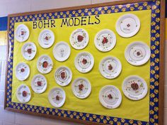 a bulletin board with paper plates and ladybug magnets on it, along with the words bohr models