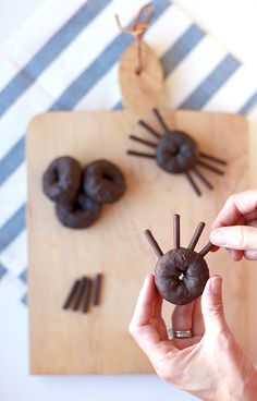 a person holding up a chocolate donut in the shape of a spider