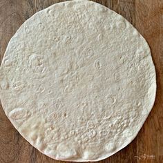 an uncooked tortilla sitting on top of a wooden table