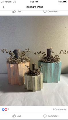 three small wooden vases sitting on top of a white sheet covered table next to each other