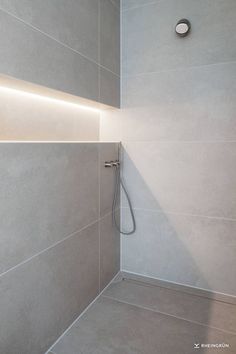 the shower head is mounted on the wall next to the tiled bathtub in this modern bathroom