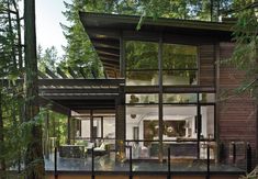 a house in the woods with large windows and lots of glass on it's sides