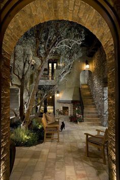 an archway leading to a living room and dining area with stone walls, wood furniture and stairs