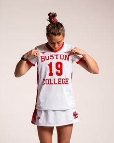 a female basketball player in white and red uniform with her hands on her hips, looking down