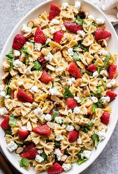 strawberry chicken and spinach pasta salad on a white platter with text overlay