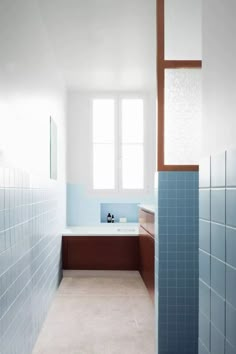 an empty bathroom with blue tiles on the walls and floor, along with a bathtub