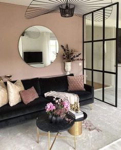 a living room with a black couch and mirror on the wall, pink walls and flooring