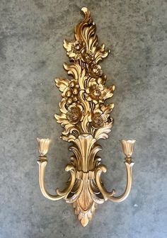 Iconic in its design and reminiscent of Old-Hollywood glamour, this ornately carved gold gilt wall sconce glams up your wall lending an inherent sense of luxury to any space.  circa 1960s this stunning tall candleholder wall sconces is carved out of a plastic composite material popular at the time and finished in antique gold gilt paint. It holds a single candle and has ready hardware for hanging. Measures approximately a little under 27" Long x 10 " Wide.x 5" Deep x 0.5" Thick  Marked MCMLXX11 4133 Syrocco Inc Made in USA on back Overall excellent vintage  condition with no cracks or breaks. Minor loss of gilt possible. Please preview all pictures for a more detailed condition as pictures are a part of the description. Love Vintage ? Looking for more mirrors like this one? Explore my shop Christmas Village Accessories, Candle Holder Vintage, Gold Home Decor, Single Candle, Vintage Mirrors, Hollywood Regency Style, Vintage Candle Holders, Composite Material, Hollywood Regency