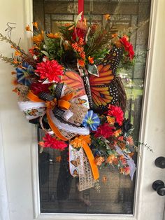 a colorful wreath with butterflies and flowers on the front door is hanging from a glass door