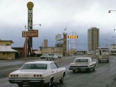 cars driving down the road in front of motels and hotels on a cloudy day