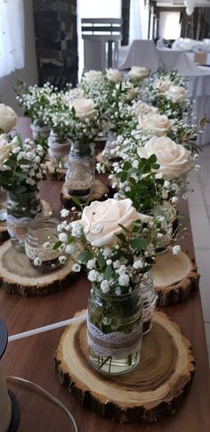 several mason jars filled with white flowers on top of wooden slices