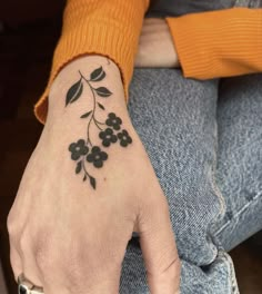 a woman's hand with a small black flower tattoo on it