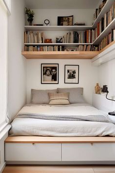 a bed sitting under a book shelf next to a window