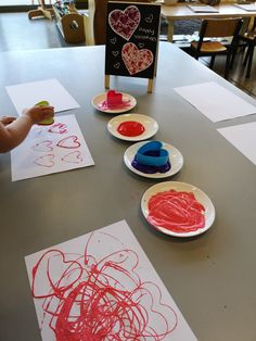 children are painting hearts on paper plates with red crayons and watercolors