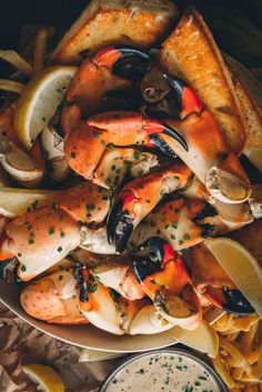 a plate full of crab legs and fries with dipping sauce