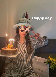 a woman wearing a birthday hat holding a cake with lit candles