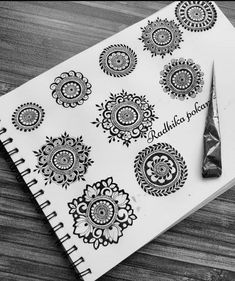 an open notebook with black and white henna tattoos on it next to a pair of scissors