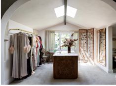 an open closet with clothes on hangers and a vase full of flowers in the window