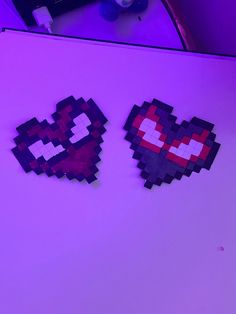 two pixel heart shaped magnets sitting on top of a refrigerator