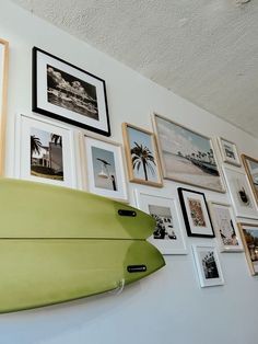 a surfboard mounted to the side of a wall with many pictures hanging on it