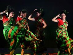 three women in colorful dresses are dancing on stage