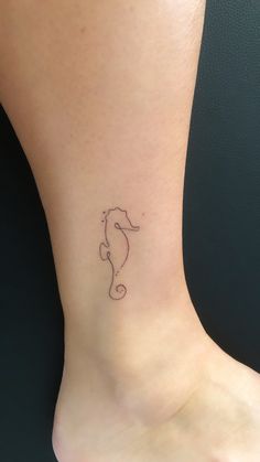 a small tattoo on the ankle of a woman's foot, depicting a sea horse