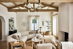 a living room filled with furniture and a fire place under a wooden beamed ceiling